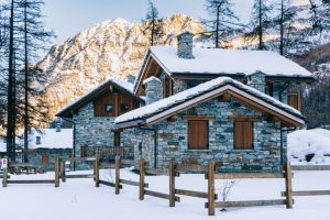 Snowy stone cabin with mountains in the background in Trentino, Italy