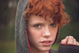 Person with curly red hair wearing a hood