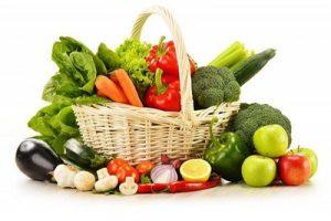 A basket of vegetables with lettuce, bell peppers, celery, cucumbers, eggplant, mushrooms, garlic, onion, broccoli, and carrots.