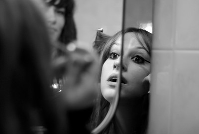 Person putting on mascara in a mirror