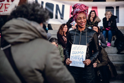 An African-Italian woman showing a sign to protest against patriarchal society