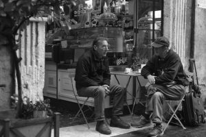 Two men talking, smoking and drinking coffee in a café in Italy