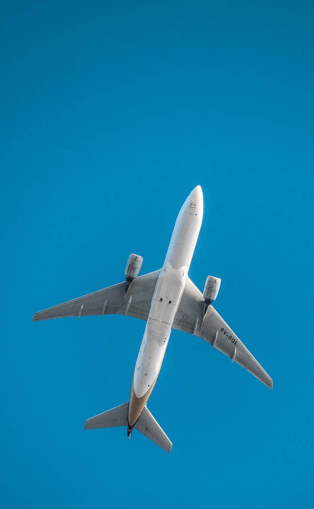 A low angle shot of a flying white and grey plane in the sky