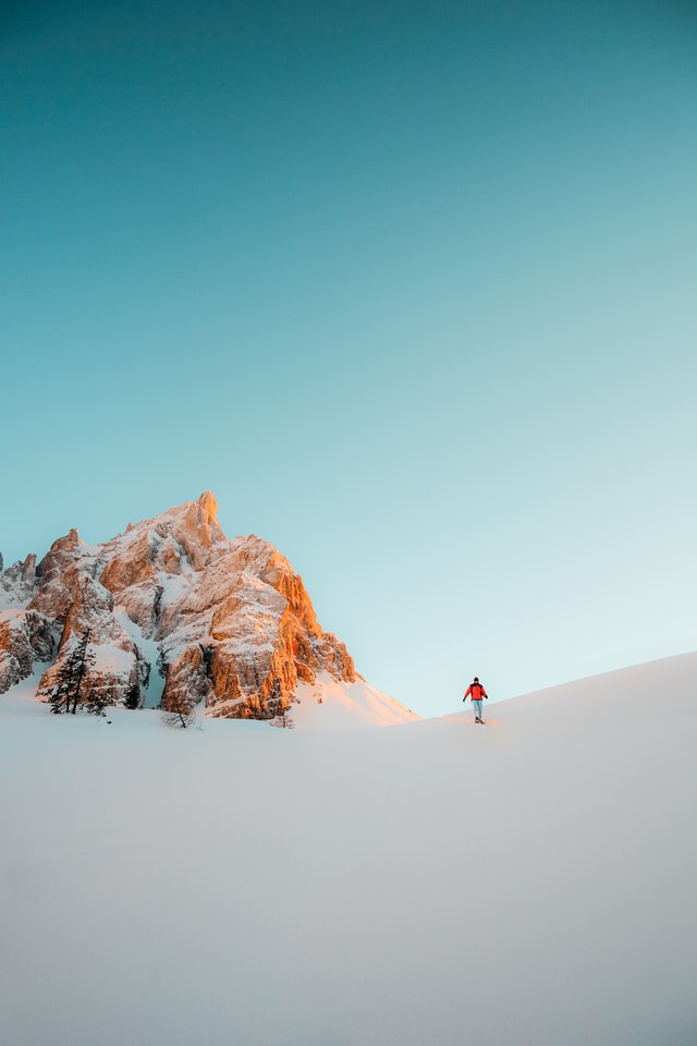 A person with a red jacket walking in the snow in the Dolomiti