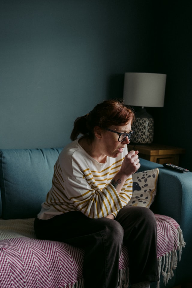 A woman coughing on a couch