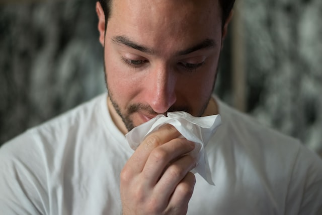 A man sneezing in a tissue because he has a cold