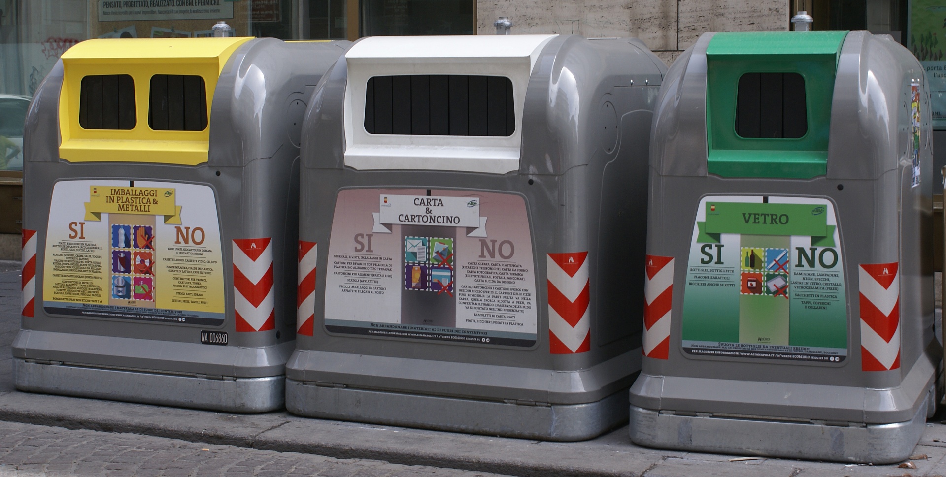 Three recycling bins (plastic, paper, and glass) on an Italian street