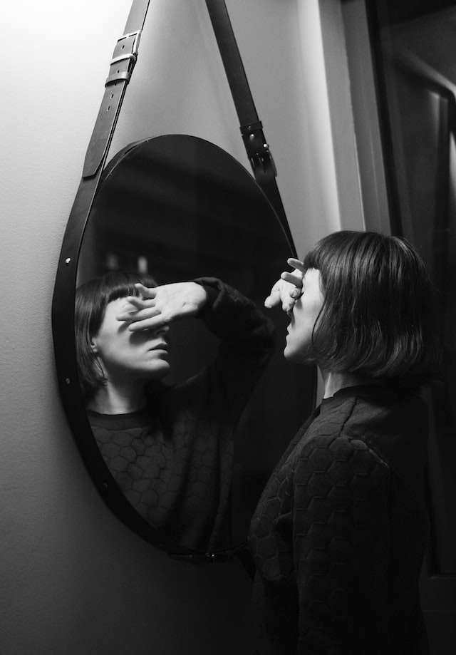 Woman in black long sleeve shirt standing in front of a mirror