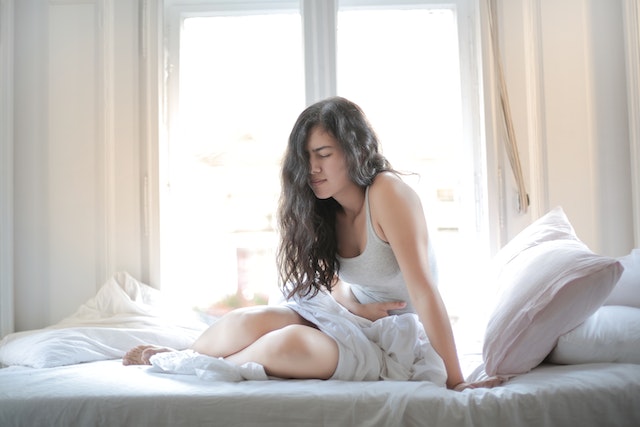 A woman lying in bed with stomach ache