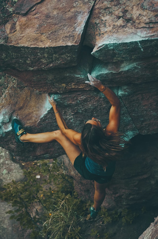 Person free solo climbing on a large boulder