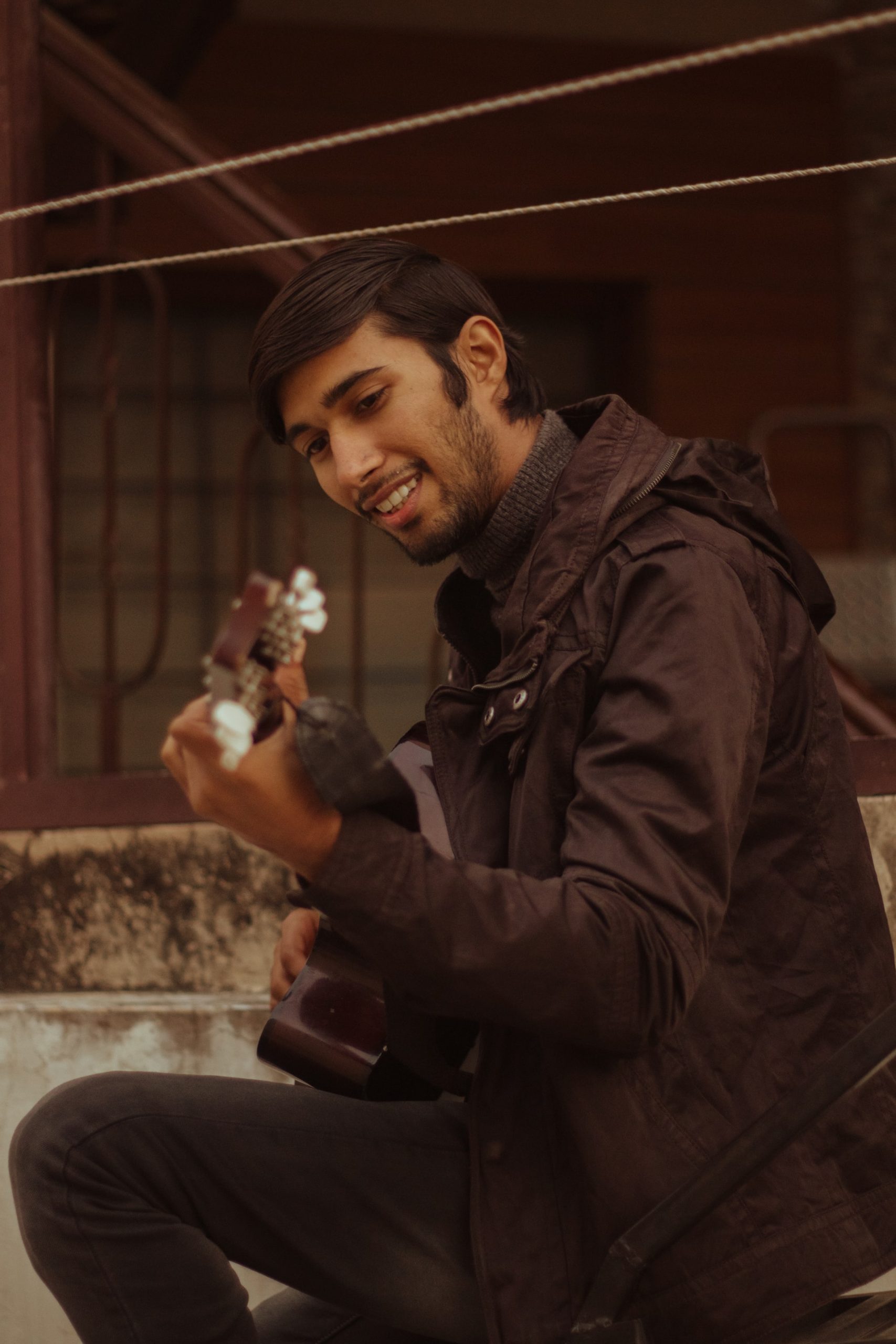 A man in a brown jacket playing a guitar