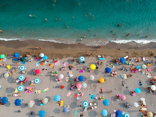 People at the beach; numerous coloured umbrellas