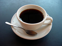 A small cup of black coffee with a spoon on the saucer.