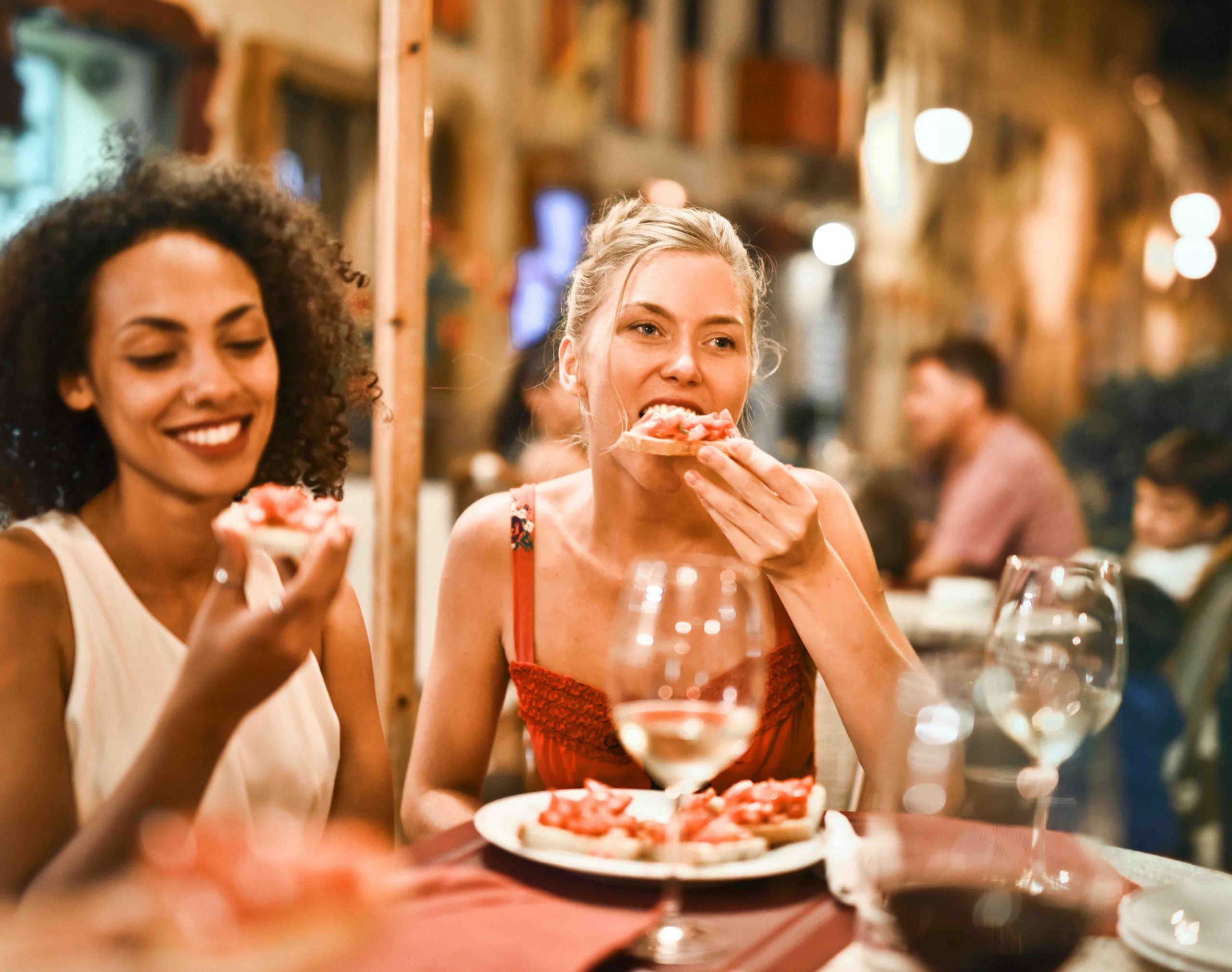 Two women eating pizza at a restaurant