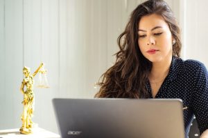 Lawyer working on a laptop. To their left is a trophy-sized lady justice on a desk.