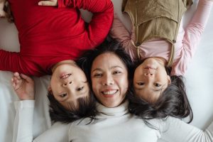 Aerial shot of mother and her two children lying down and smiling.