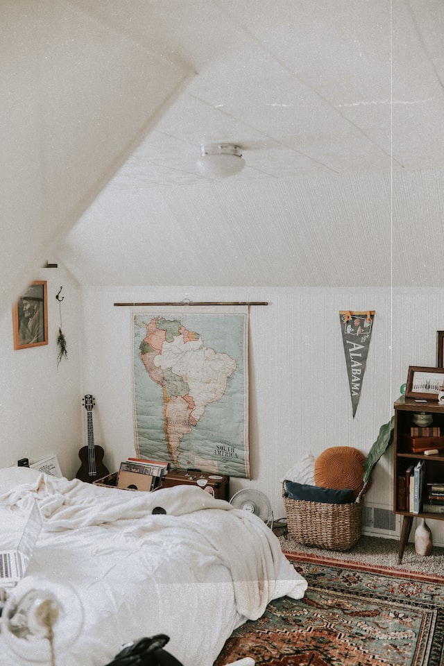 A bedroom with a white bed and several objects on the floor