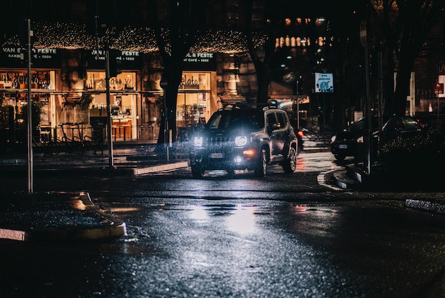 A car stopped in front of a bakery cafe in Rome while it is raining