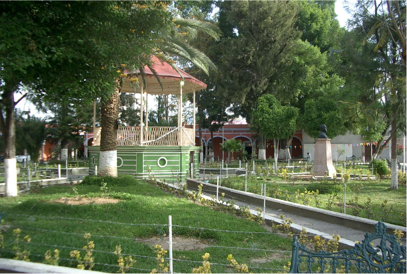 Photograph of a grassy area with paths toward a gazebo. The gazebo is red on the bottom, off white in the middle, and red on the top.