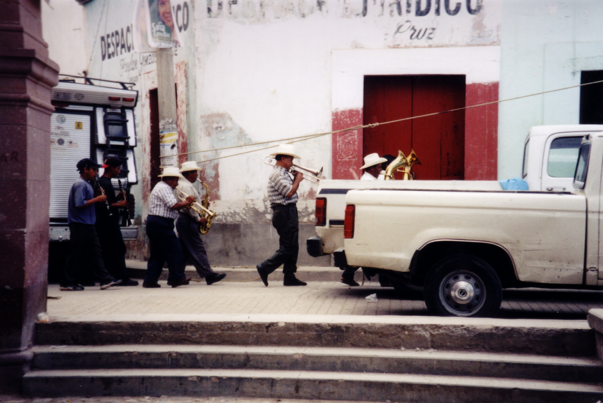 Band with brass and wind instruments processing from left of frame to right of frame