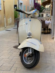 White vespa parked on the street.