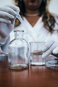 Scientist pipetting liquid from one beaker to the another.