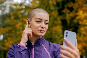 A person touching their earbuds and holding a smartphone