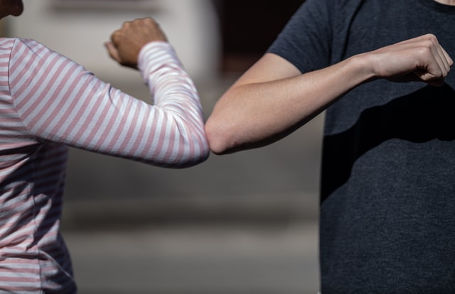 Two people greeting each other with their elbows