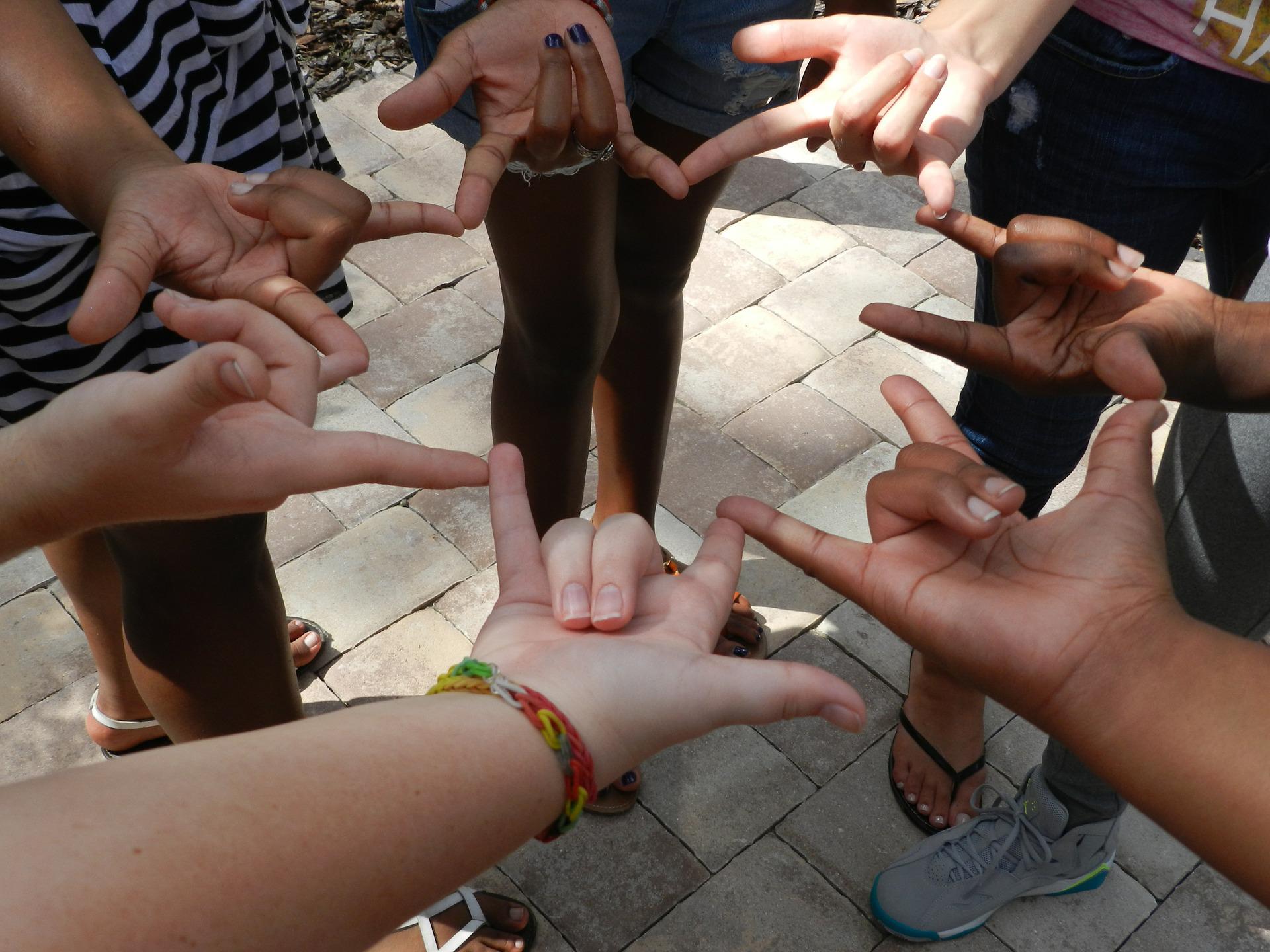 People in circle making the sign of "love"